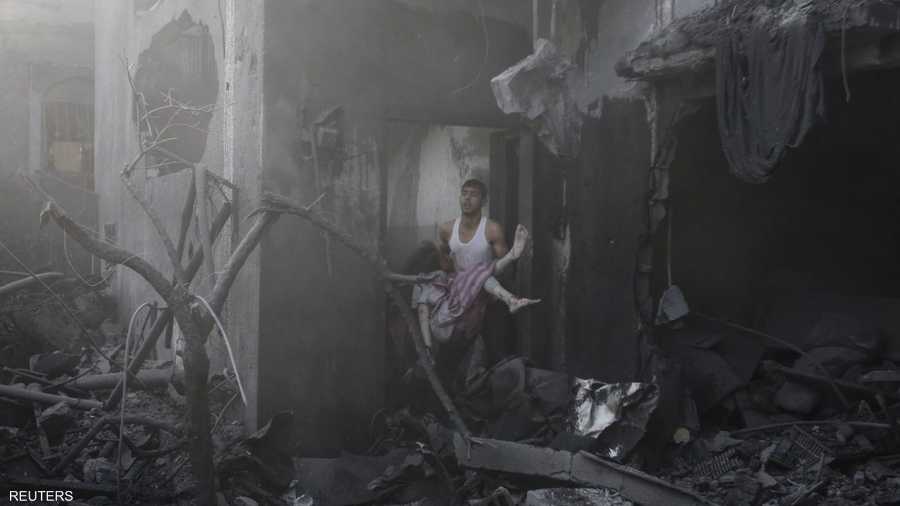 فلسطيني يحمل جثة امرأة قتلت في قصف إسرائيلي