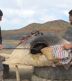 شباب يجسد فكرة طهي الخبز التقليدي على أفران الطين