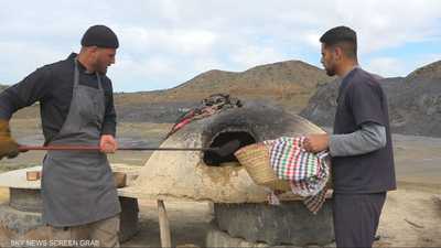 شباب يجسد فكرة طهي الخبز التقليدي على أفران الطين
