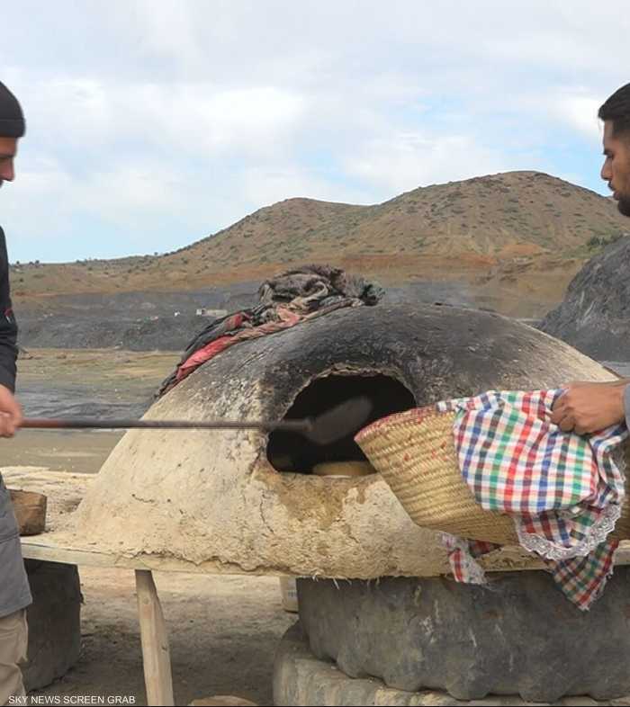 شباب يجسد فكرة طهي الخبز التقليدي على أفران الطين