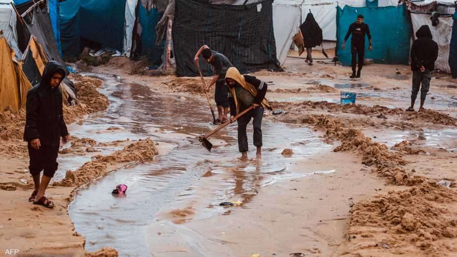 يحفرون مجرى لمياه الأمطار لتجنب دخولها للخيام